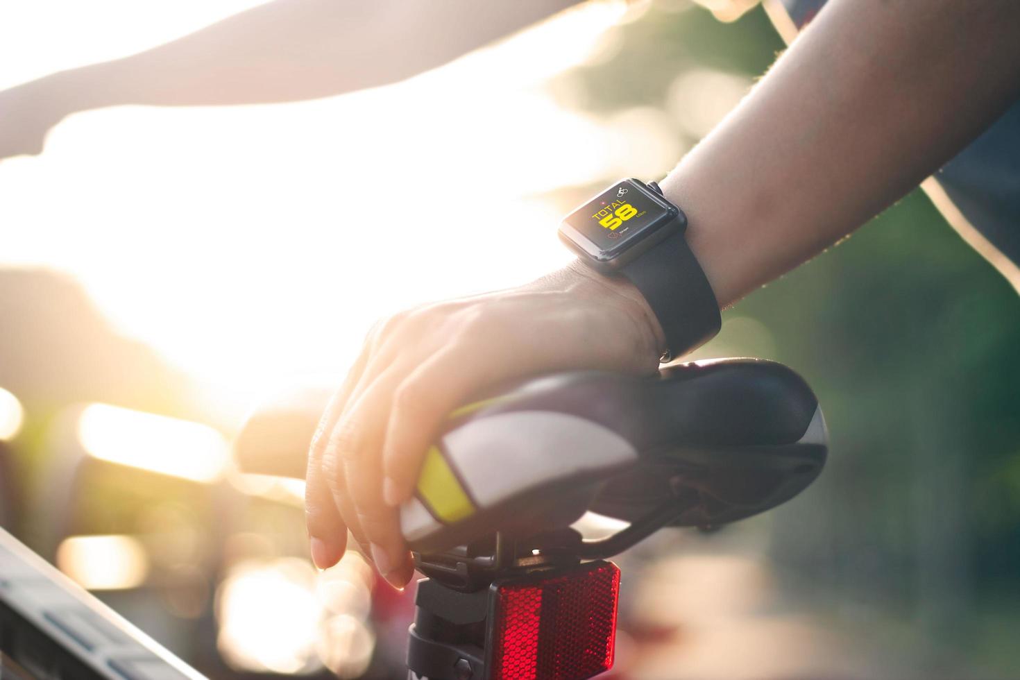 vrouw fietser hand met slimme horloge op zadel fiets op zomer trail. foto