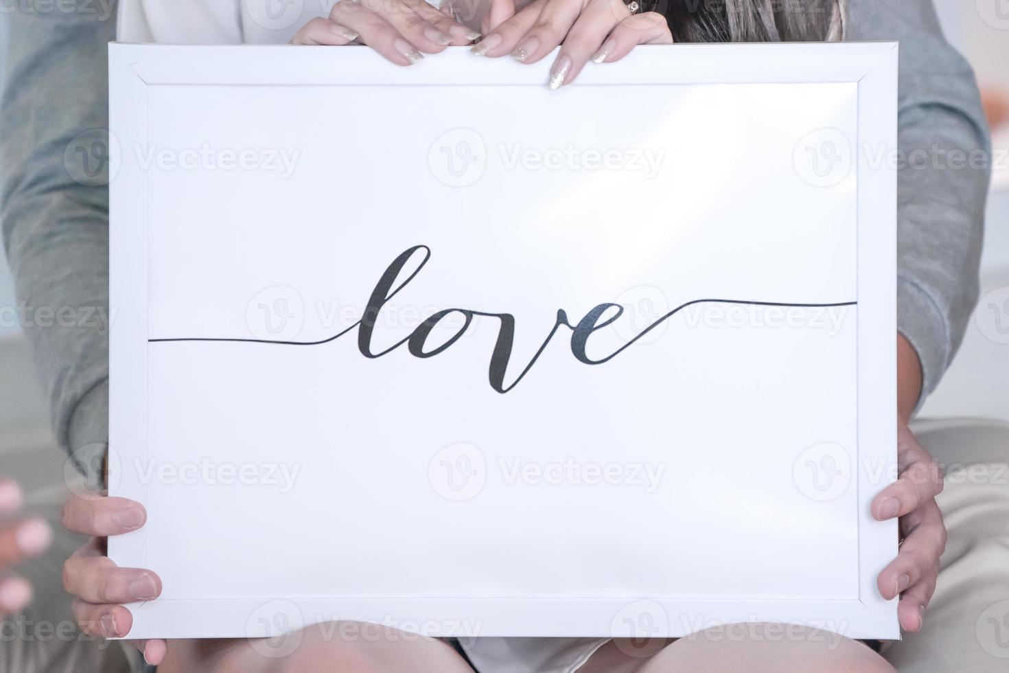 liefdesbrief in het witte frame en de achtergrond, vastgehouden door bruid en bruidegom erachter. foto