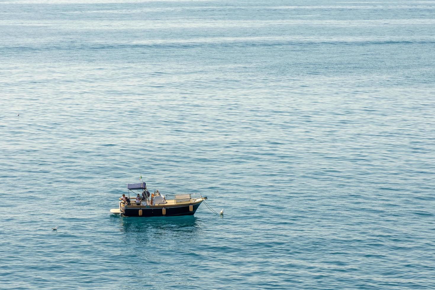 manarola, liguria, italië, 2019. toeristenboot voor de kust bij manarola, liguria, italië op 20 april 2019. drie niet-geïdentificeerde mensen foto