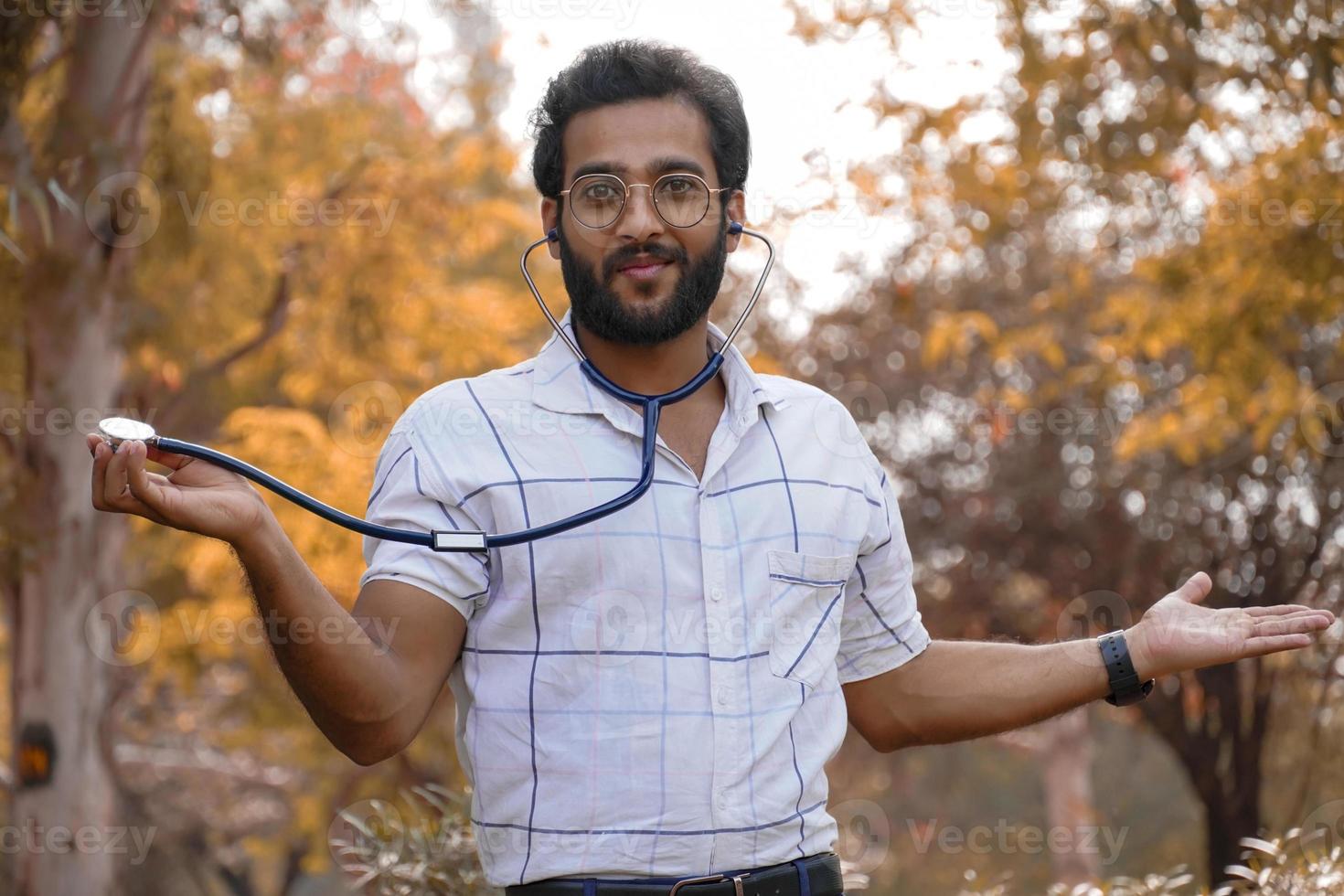 een opgewonden student die een stethoscoop toont - student met een stethoscoop medisch onderwijsconcept foto