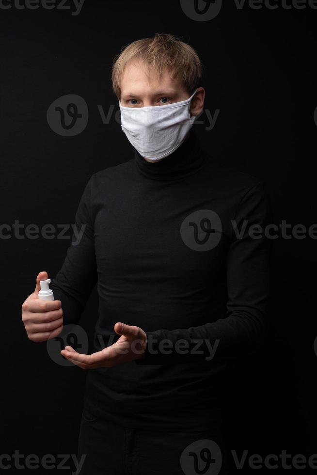 een man met een medisch masker laat zien hoe hij zijn handen moet behandelen met een ontsmettingsmiddel. coronavirus bescherming. foto