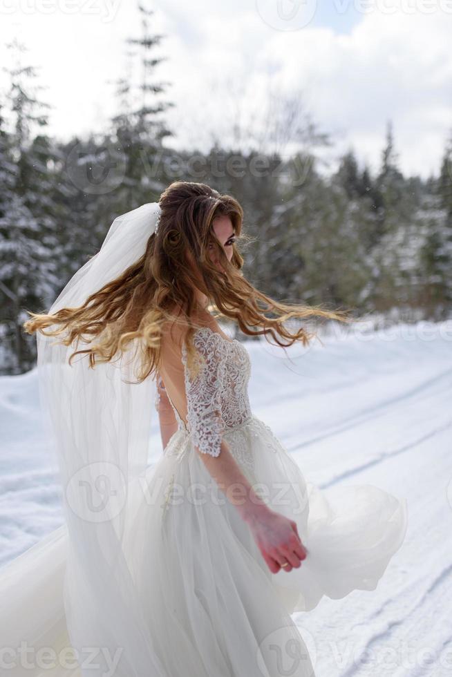 de bruidegom leidt zijn bruid bij de hand naar een eenzame oude beuk. winterse bruiloft. plaats voor een logo. foto