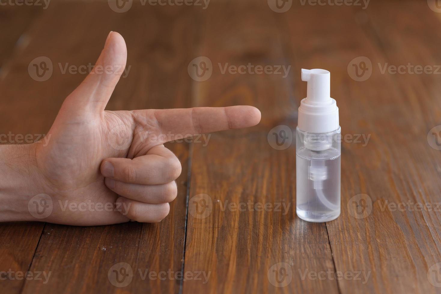 mannenhand wijst naar een antisepticum. geschoten op een houten tafel achtergrond. foto