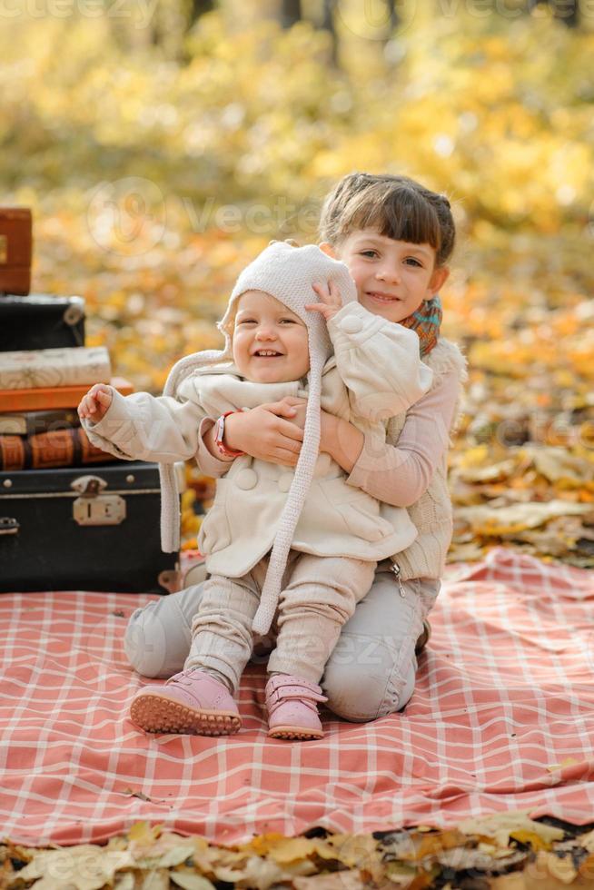 twee zusjes knuffelen op het strand tijdens een picknick in het park. herfst tijd. foto