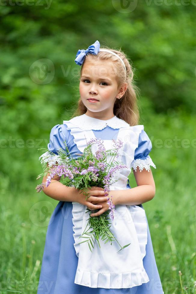 portret van een klein schattig meisje verkleed als Alice. gestileerde fotoshoot in de natuur. foto