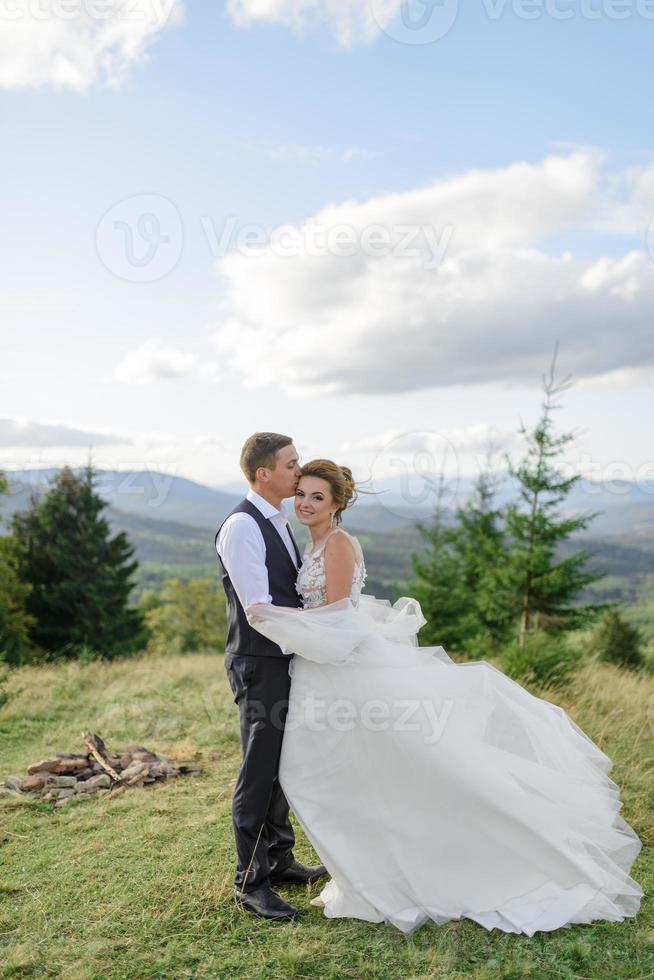 huwelijksfotografie in de bergen. de bruid en bruidegom knuffelen stevig. foto