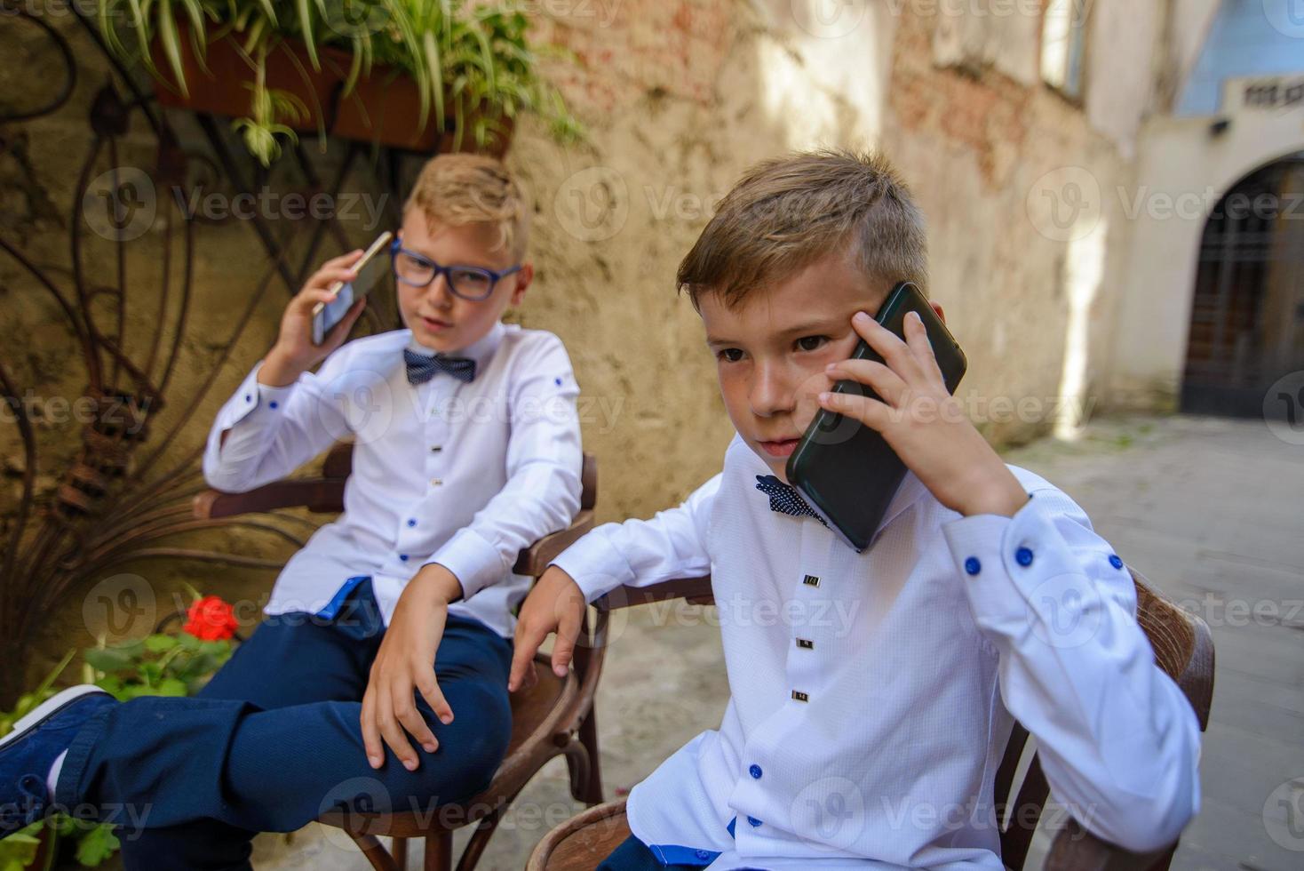 twee kleine jongens, broers zijn gekleed in een pak. kinderen staan in het park en knuffelen. foto