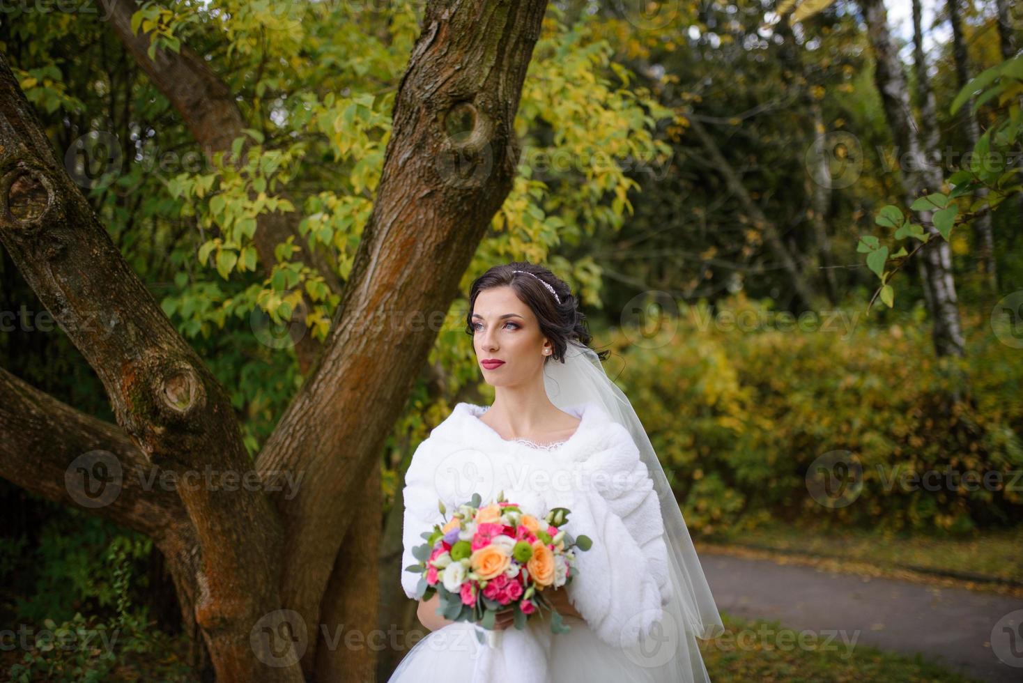 portret van een eenzame bruid op een achtergrond van een herfstpark. het meisje zocht haar toevlucht onder een sluier waarmee de wind zich ontwikkelt. foto