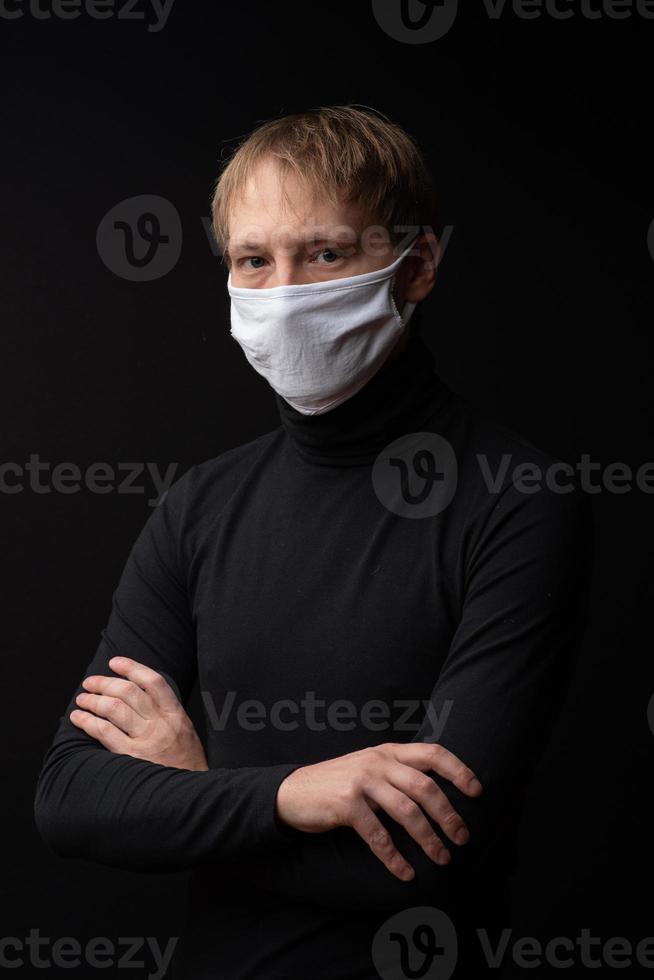 een man met een medisch masker kijkt naar de camera. geschoten op een zwarte achtergrond. foto