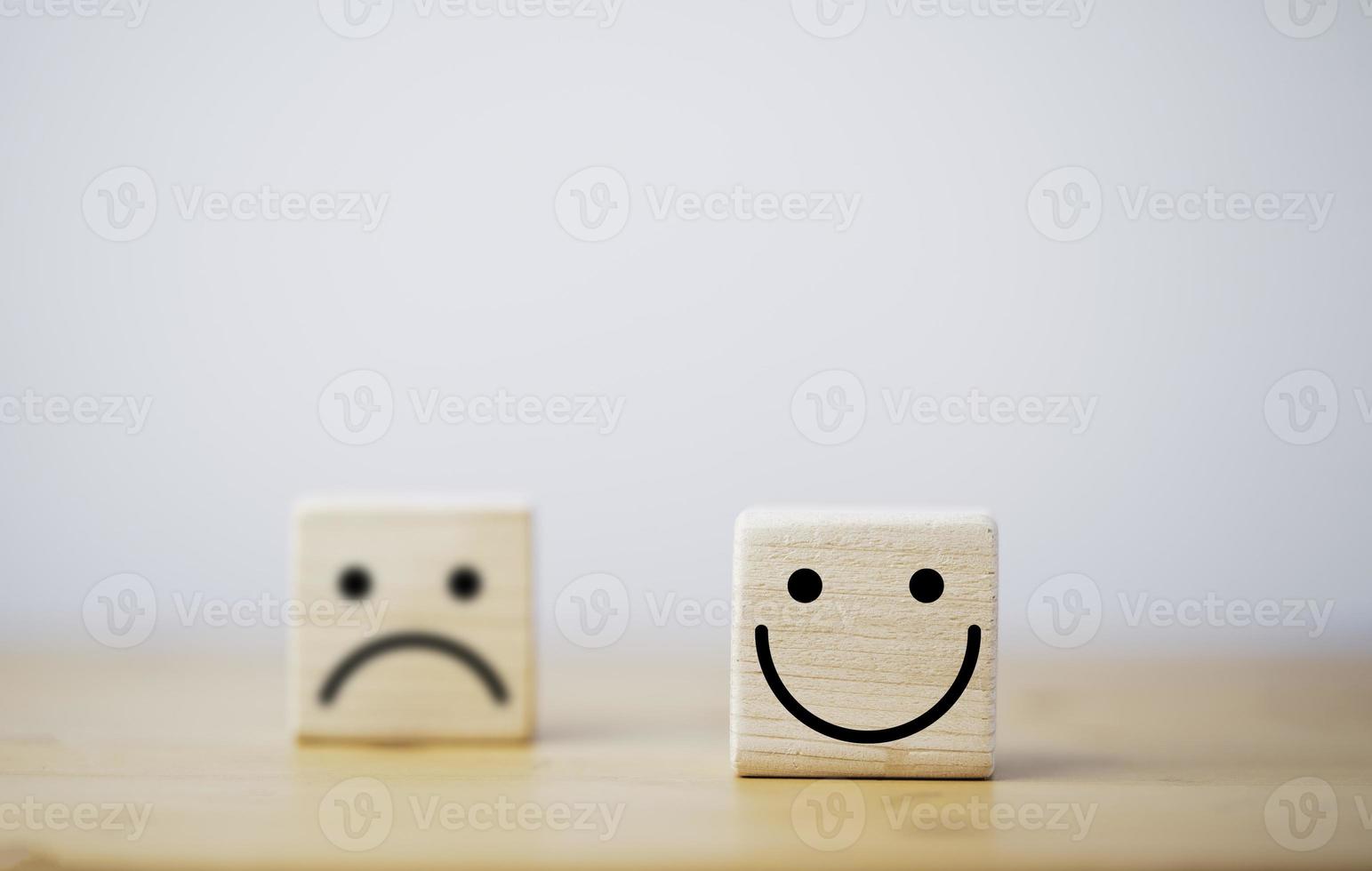 focus van glimlachgezicht en defocus van droevig gezicht op houten blokkubus voor positief mindset-selectieconcept. foto