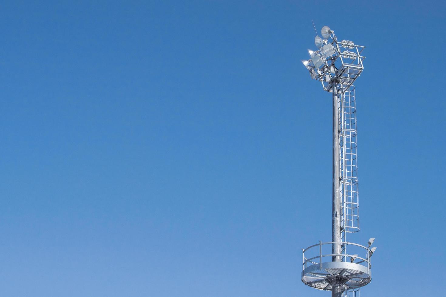 hoge metalen mast met schijnwerpers tegen een heldere hemel. foto