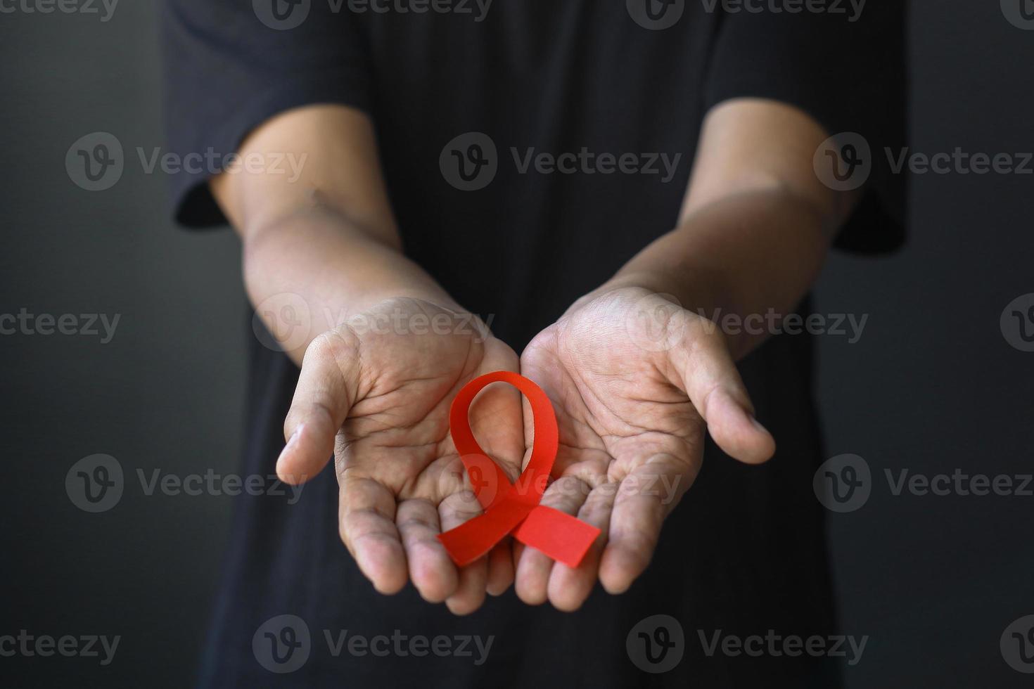 wereld aids dag en wereld diabetes dag met mannelijke handen met rood aids bewustzijn lint. gezondheidszorg en geneeskunde concept. foto