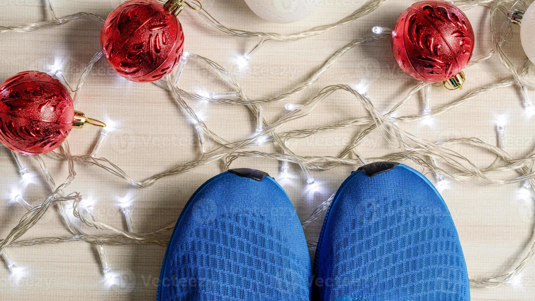 blauwe sneakers geplaatst op een houten tafel in de woonkamer. concept voor het kerstseizoen, bal rood en wit, lichten, helder, close-up, canvas schoenen foto