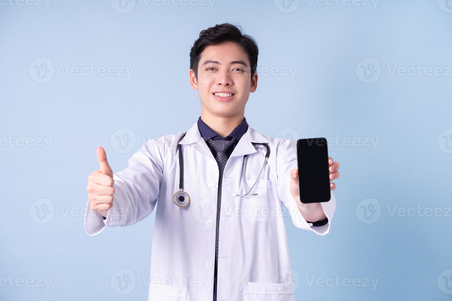portret van jonge Aziatische mannelijke arts op blauwe achtergrond foto