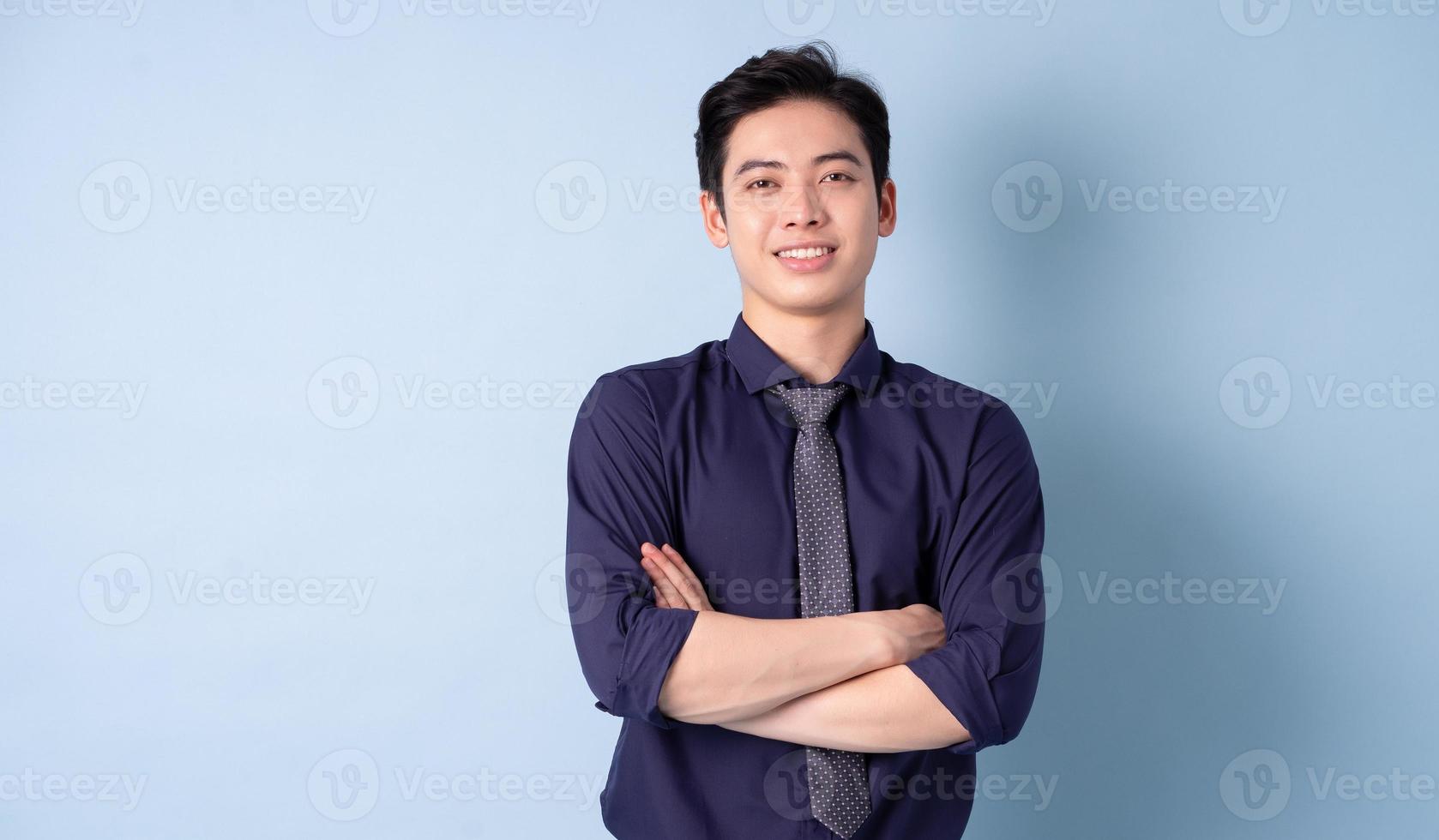 portret van een jonge Aziatische zakenman die zich voordeed op een blauwe achtergrond foto