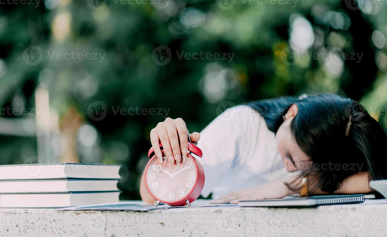 aziatische vrouw valt in slaap en zit aan een bureau met een boek. saai werk en slapeloze nachten ongemotiveerde medewerkers voelen zich ongeïnteresseerd. overwerkte vrouw stressvol werkconcept foto