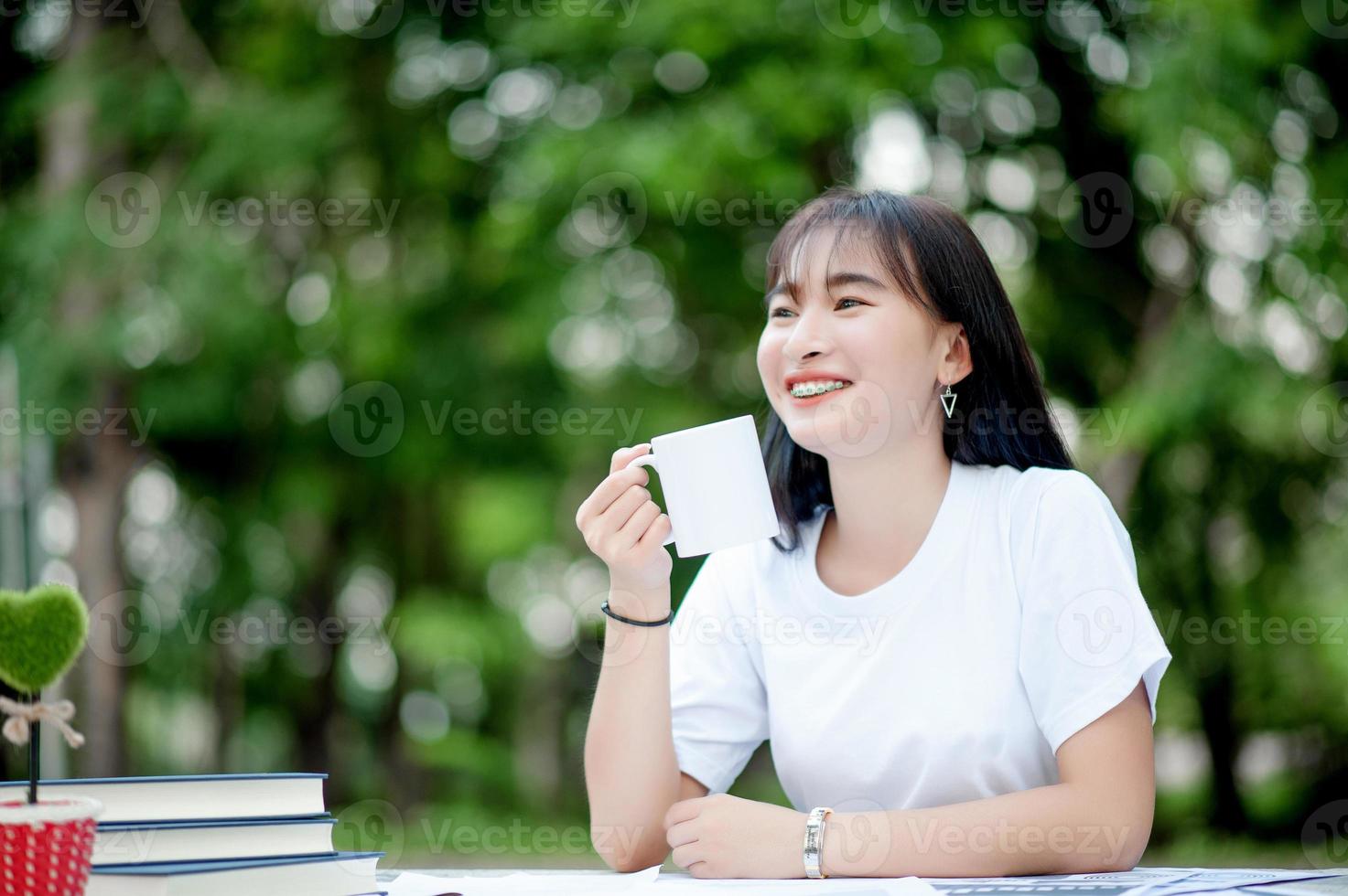 koffie drinken. portret van vrolijke jonge vrouw die thuis geniet van een kopje koffie. lachende mooi meisje hete thee drinken in de winter. drink koffie uit een witte mok in de hand thee drinken foto