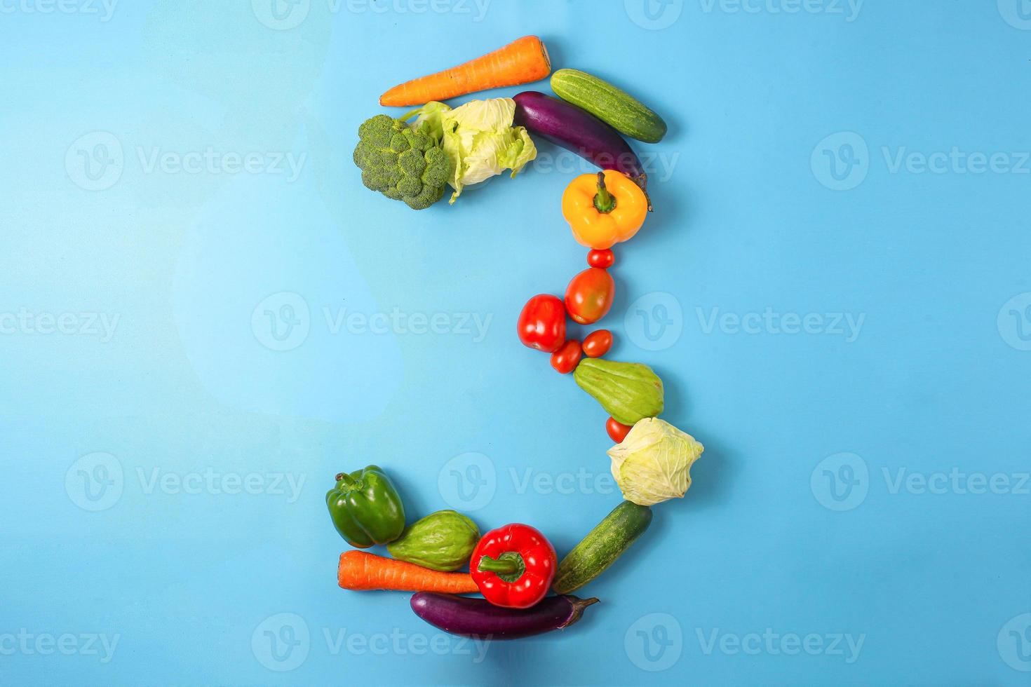 gezonde biologische groenten gevormd in nummer drie 3 op blauwe achtergrond foto