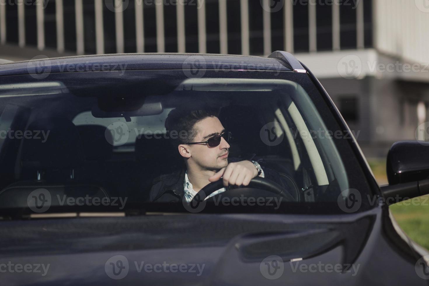 man met bril die in zijn auto rijdt foto