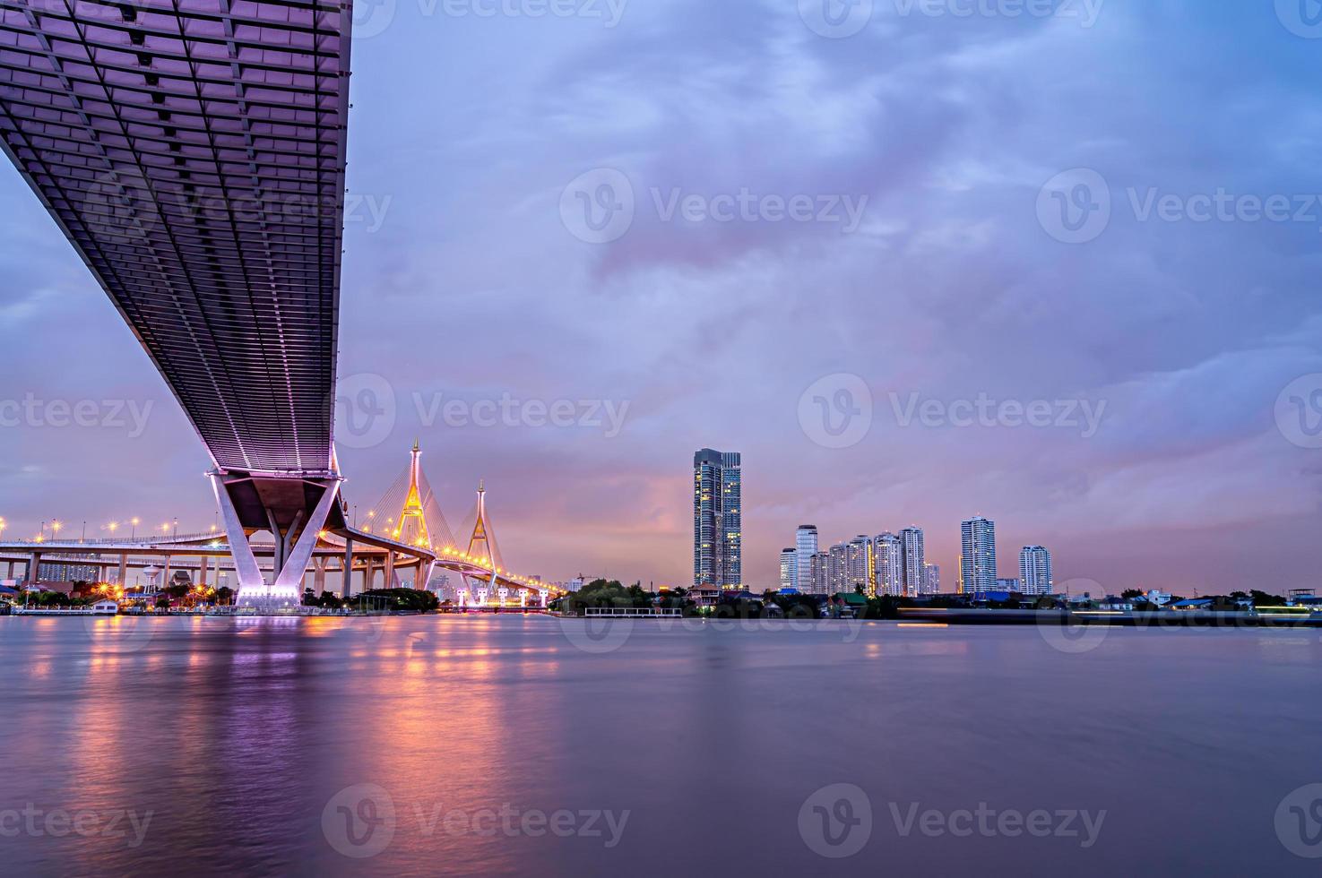 paars led-licht onder de brug over de rivier op een bewolkte dag in de lucht. bhumibol-brug, samut prakan, thailand foto