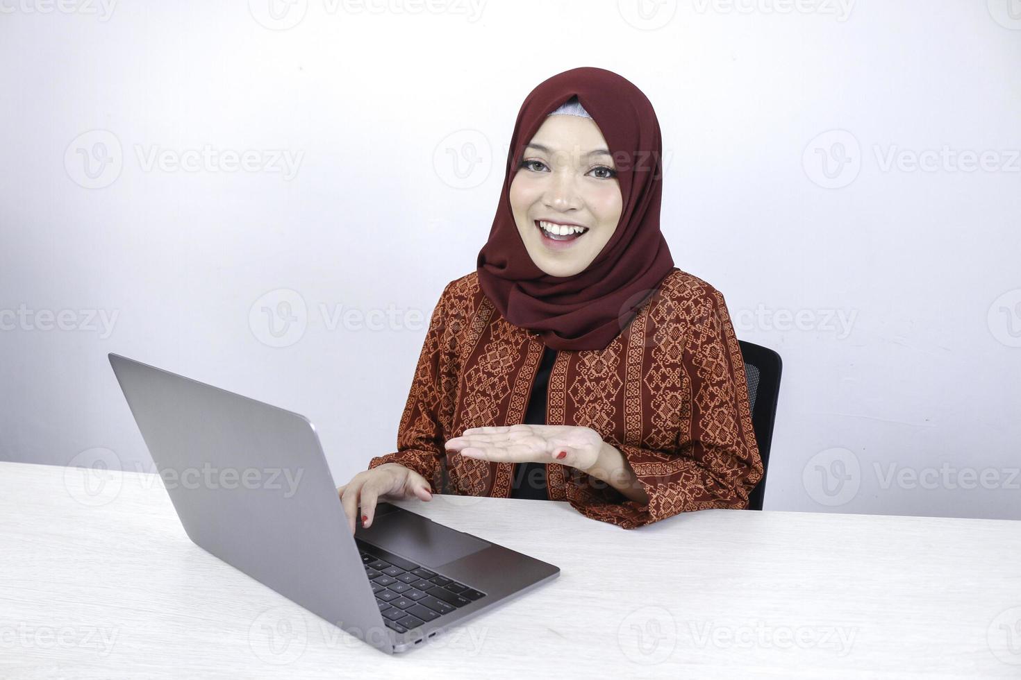 jonge Aziatische islam vrouw lacht wijzende hand bij het werken op laptop op witte achtergrond. foto