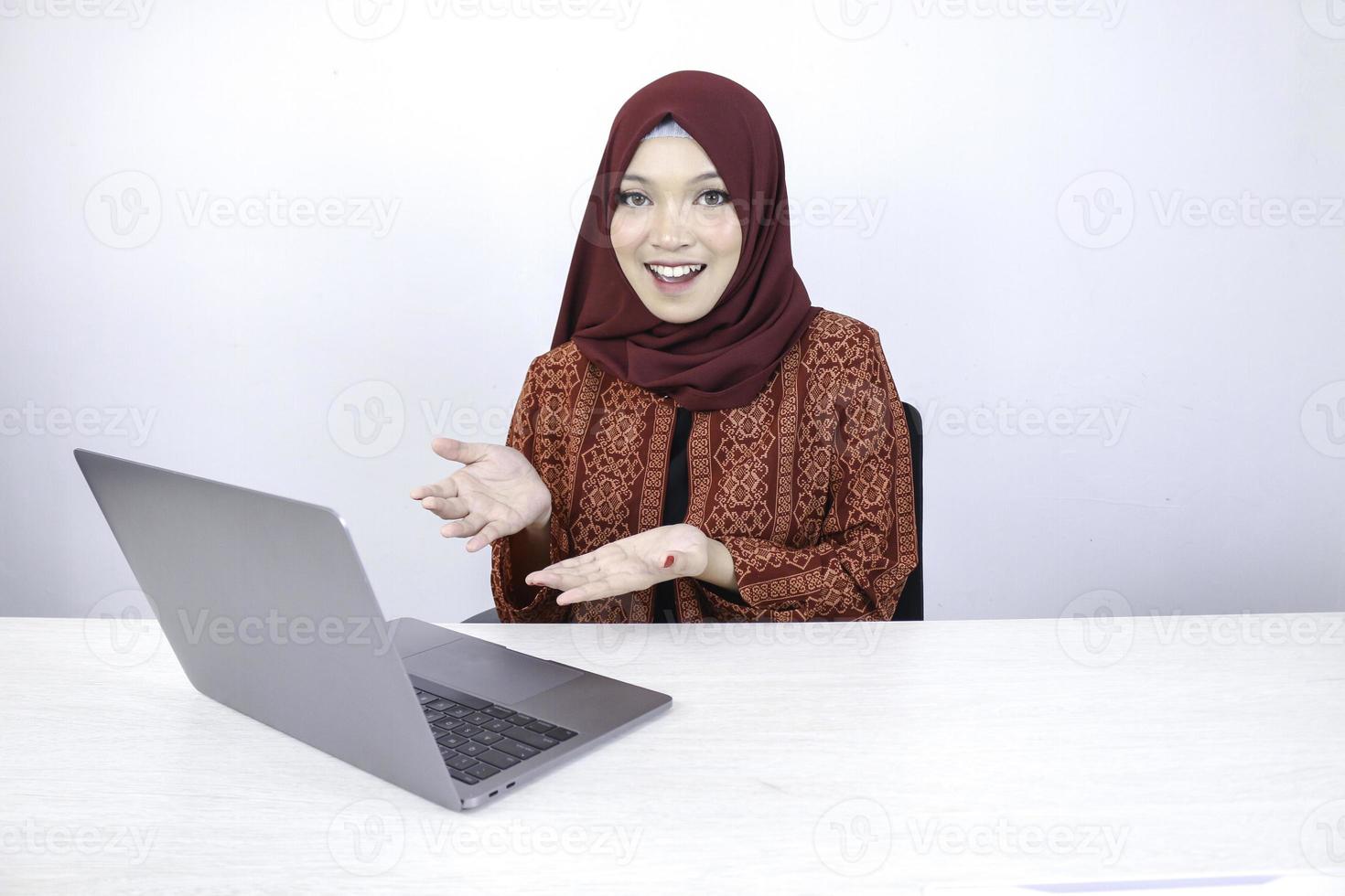 jonge Aziatische islam vrouw lacht wijzende hand bij het werken op laptop op witte achtergrond. foto