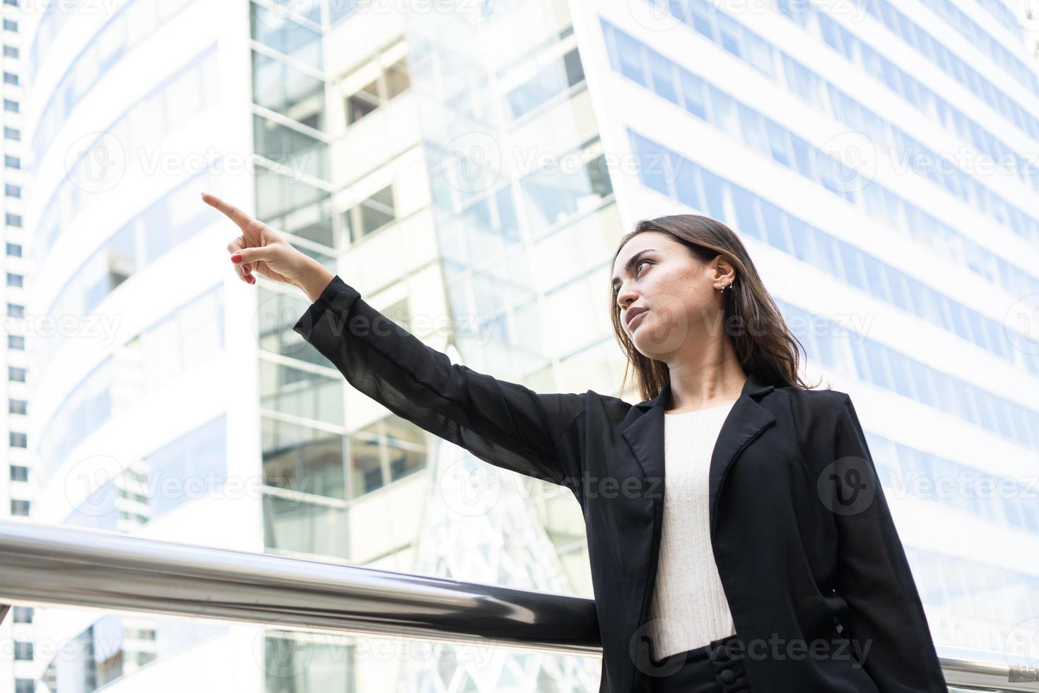 jonge slimme vrouwen staande hand wijzend naar voren voor bedrijfsconcept. aantrekkelijke brunette vrouwelijke manager wijst naar iets of wijst met de vinger naar iets foto