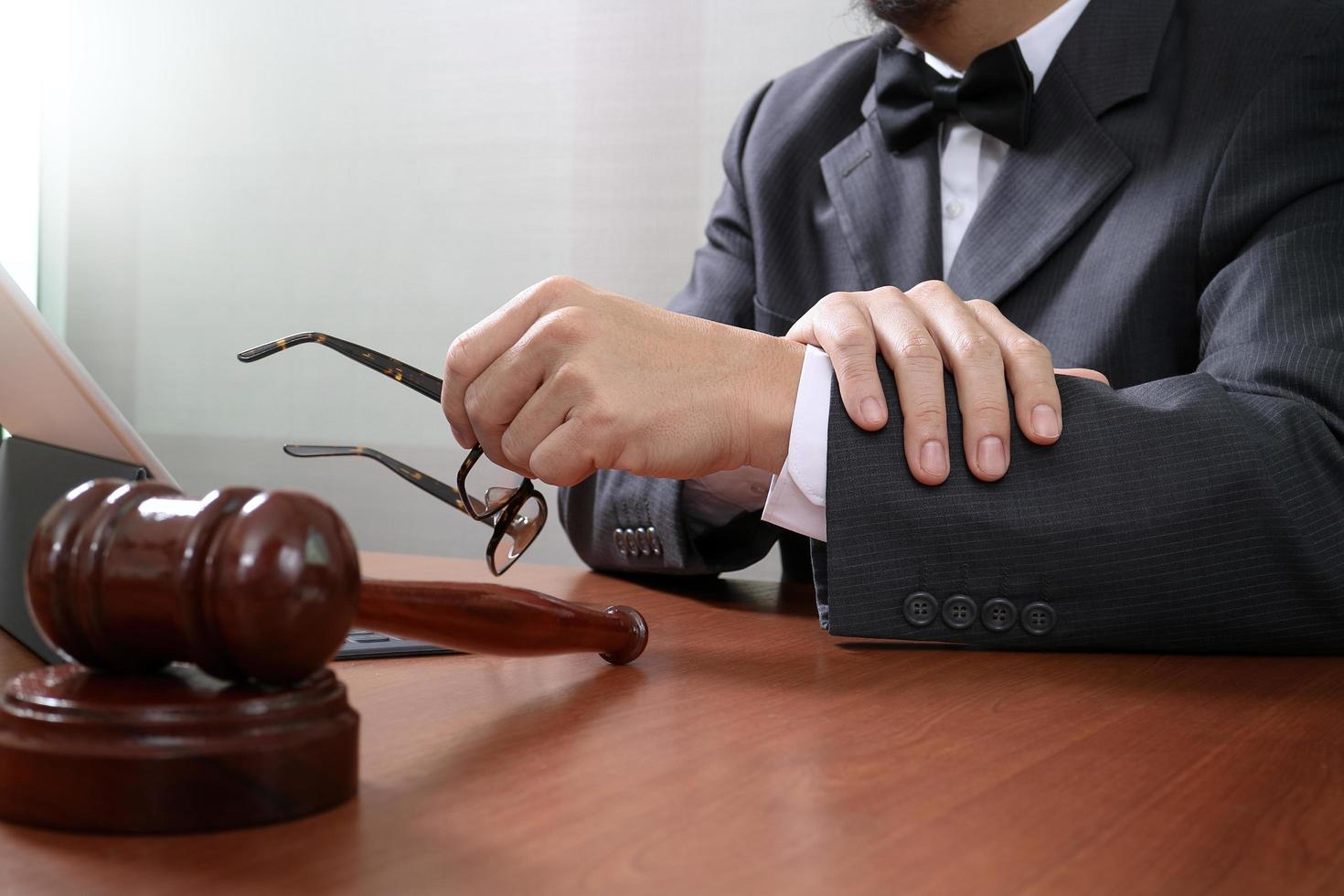 rechtvaardigheid en recht context.male advocaat hand werken met slimme telefoon, digitale tablet computer docking toetsenbord met hamer en document op houten tafel foto