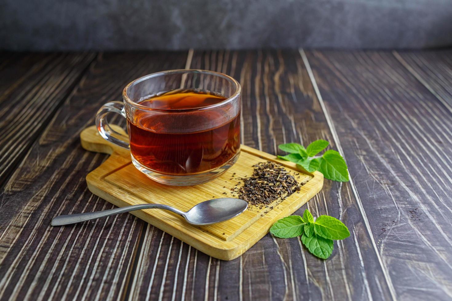 thee in glazen beker op houten achtergrond foto