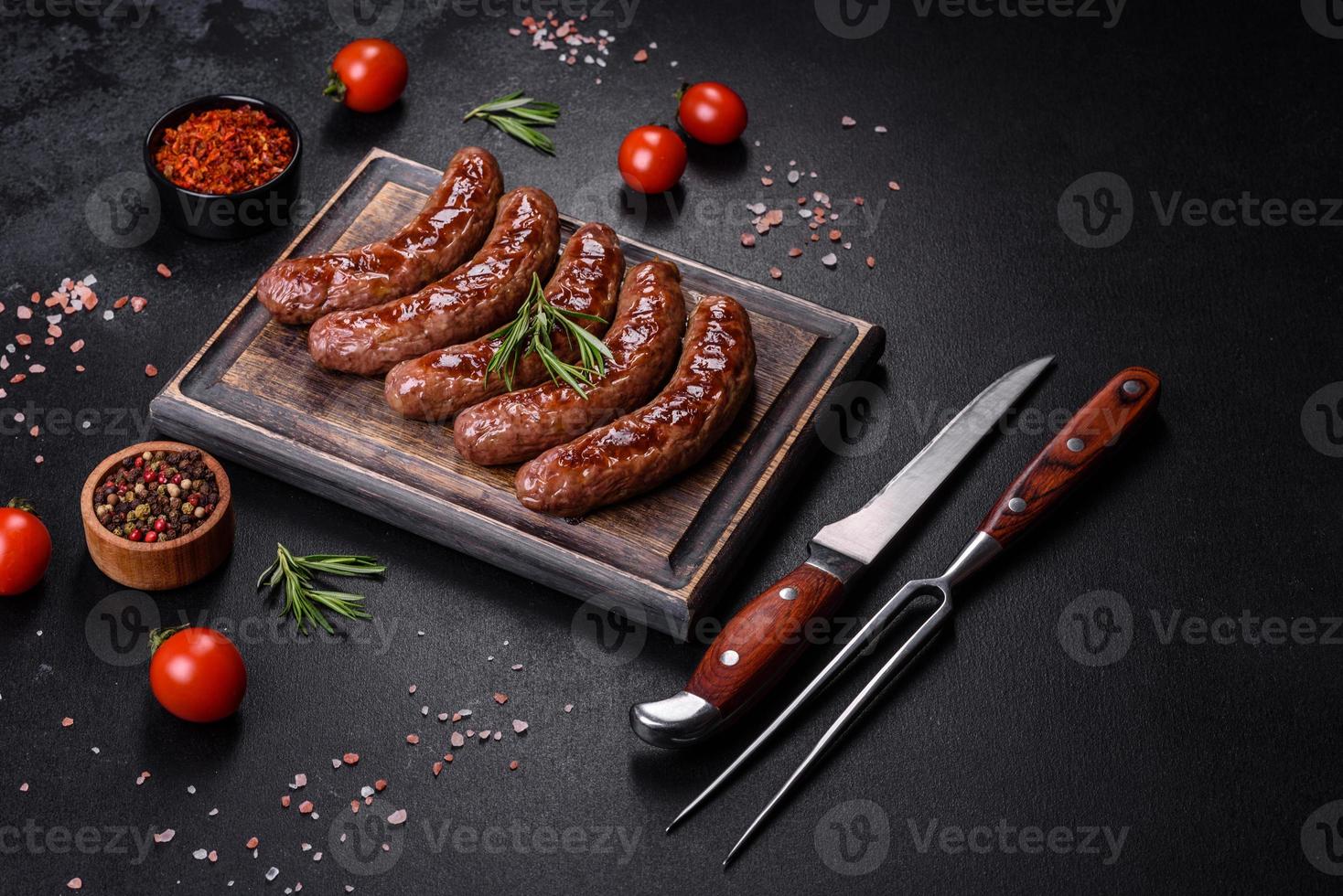 Gegrilde worstjes met ingrediënten op een snijplank op een stenen achtergrond foto