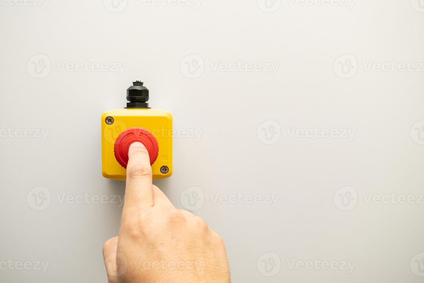 stop rode knop en de hand van de werknemer die op het punt staat erop te drukken. noodstopknop. grote rode noodknop of stopknop voor handmatig indrukken. foto