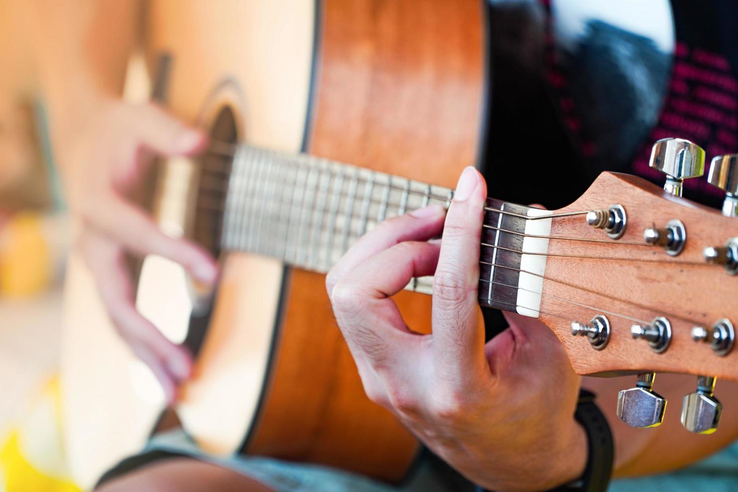 gitaar oefenen met een mooie aziatische man die gitaar speelt foto