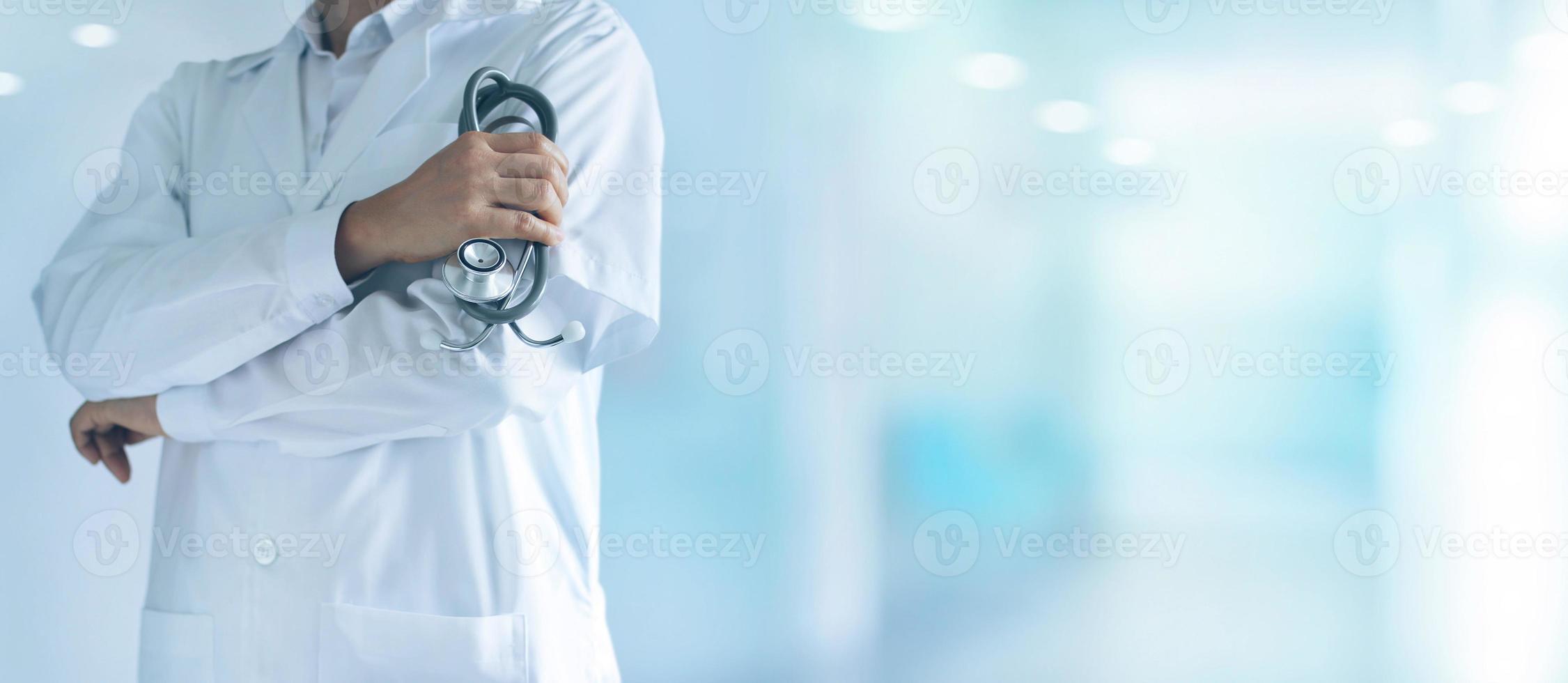 mannelijke arts met een stethoscoop in de hand die vol vertrouwen op de achtergrond van het ziekenhuis staat foto