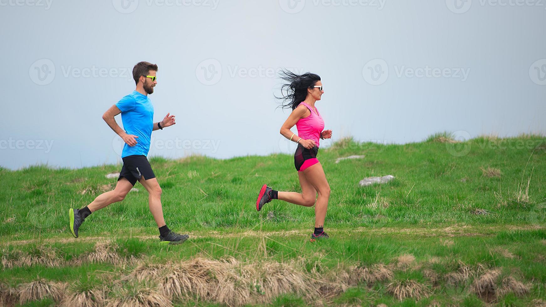 personal trainer terwijl hij zijn sportieve vrouw traint om in de weilanden te rennen foto