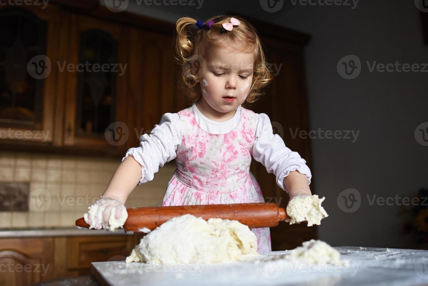 klein meisje deeg kneden foto