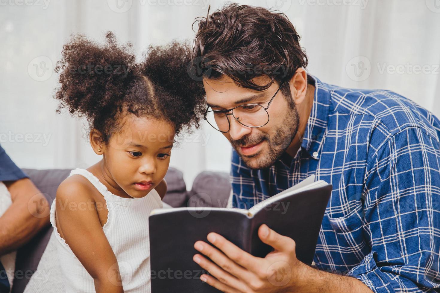 klein schattig kind dat het boek interessant vindt, houdt van lezen en leren steun van vader tot slim kindconcept. foto