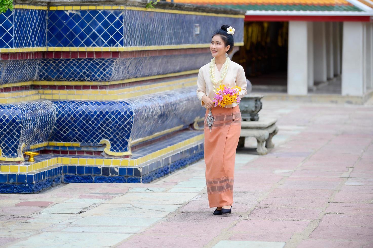Aantrekkelijke thaise vrouw in een oude thaise jurk houdt verse bloemen vast als eerbetoon aan Boeddha om een wens te doen op het traditionele songkran-festival in thailand foto