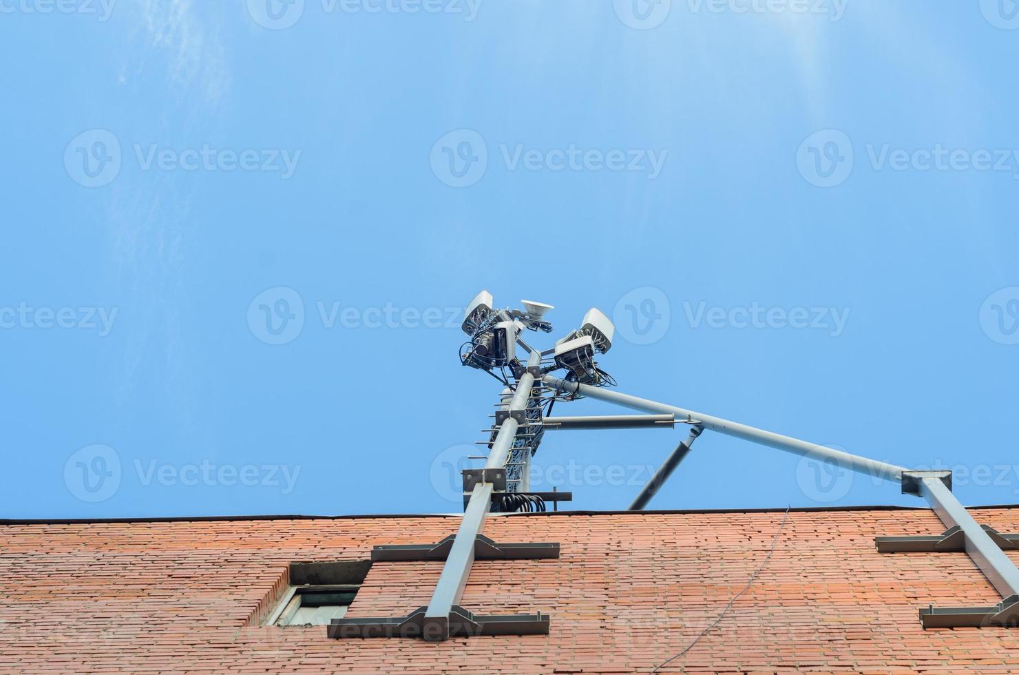 cellulaire antenne op het dak van een bakstenen huis op blauwe hemelachtergrond. foto