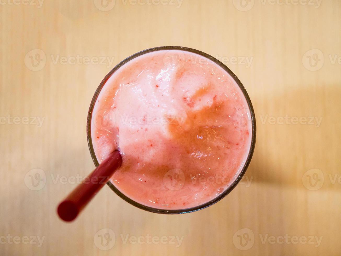 aardbeiensmoothie in glas, op houten tafel foto