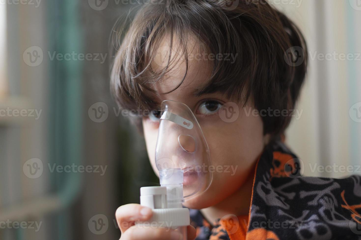 het kind inhaleert, de jongen inhaleert het medicijn door het masker foto