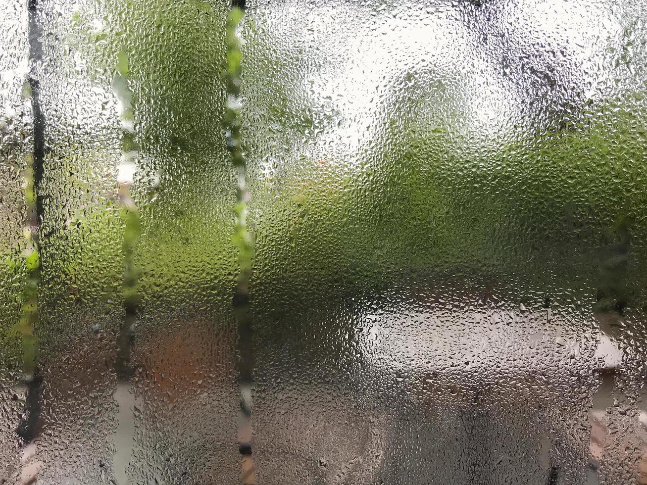 nat vensterglas van stoom condensatie waterdruppels na de regen voorgrond met onscherpte terras tuin achtergrond. selectieve aandacht. foto