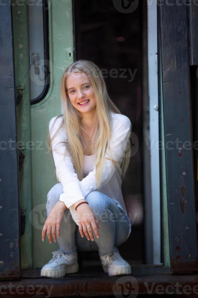 portret van een mooie blonde jonge vrouw die met de trein staat. foto