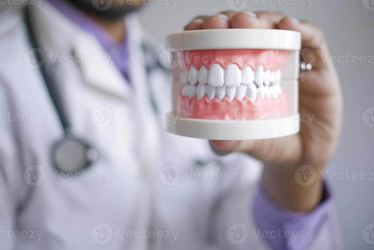 dokter hand met plastic tandheelkundige tanden model op tafel foto