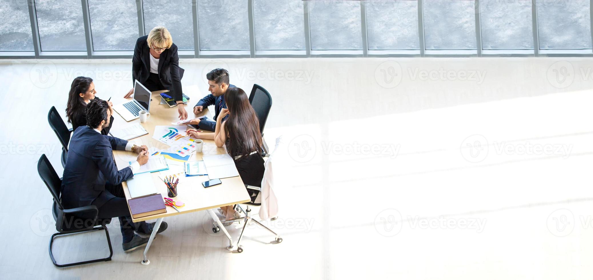 bovenaanzicht van een groep multi-etnische drukke mensen die in een kantoor werken, luchtfoto met zakenman en zakenvrouw die rond een vergadertafel zitten met kopieerruimte, zakelijke bijeenkomst concept. foto