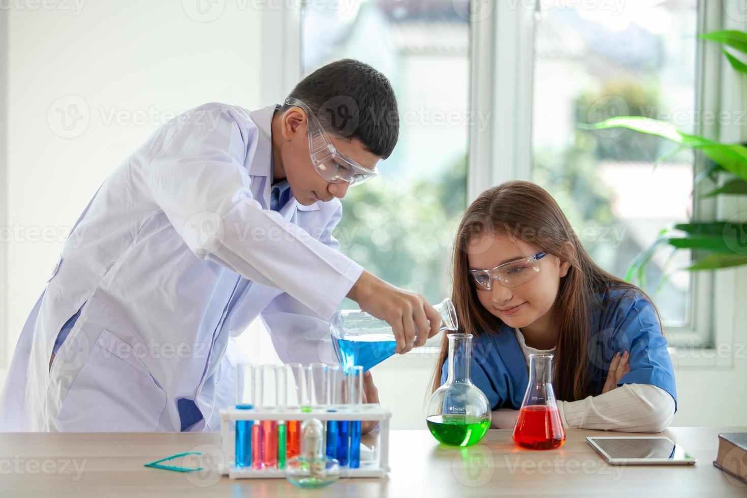 studenten mengen chemicaliën in bekers. scheikundestudent mengt chemicaliën in de natuurkundeles foto