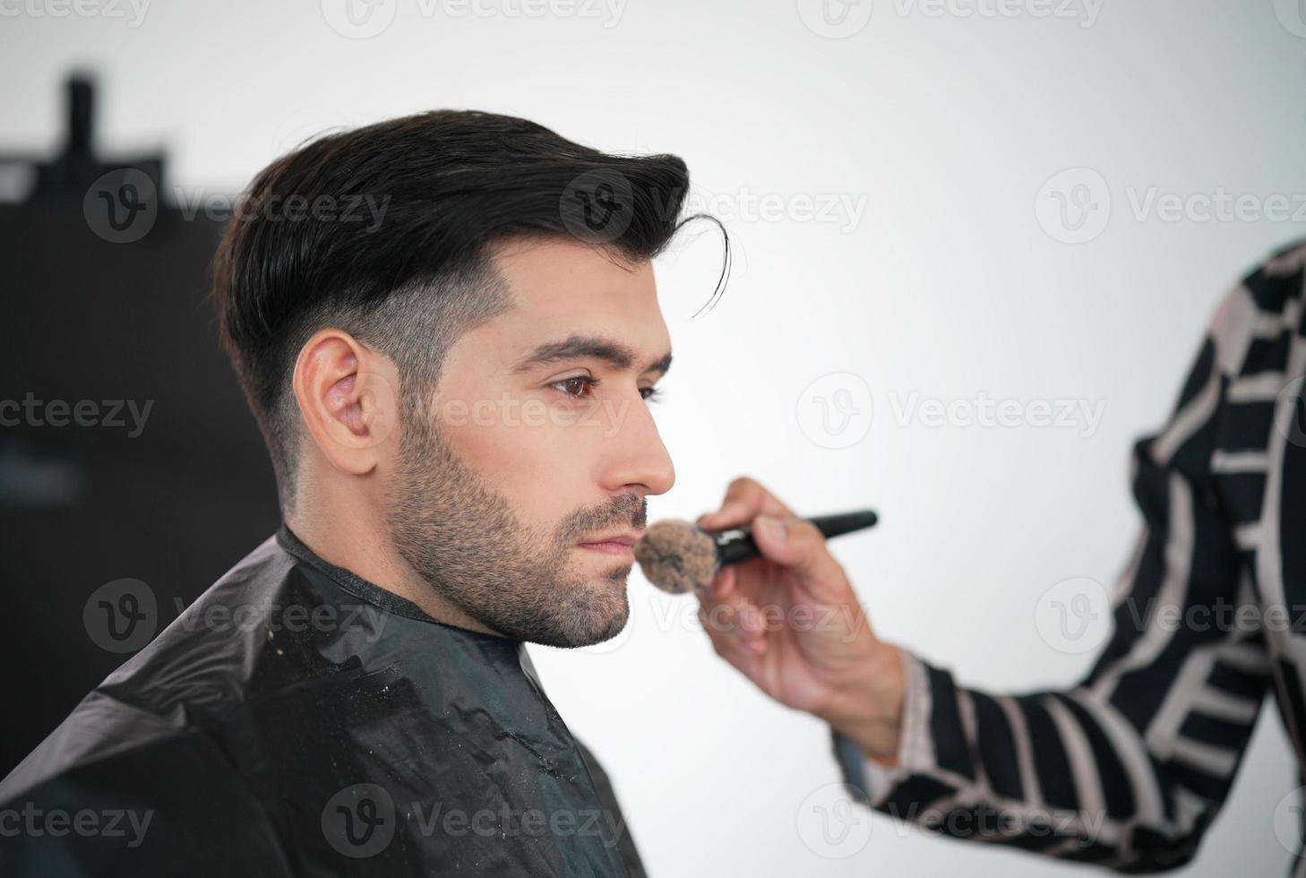 portret van knappe man was make-up door kunstenaar op zijn gezicht. foto