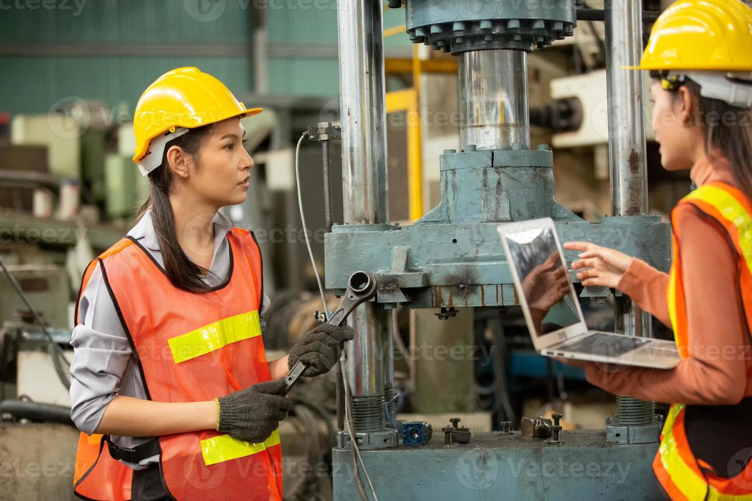 twee vrouwelijke werknemers werken op de fabriekslocatie en controleren de machine in de productlijn of producten op de locatie. ingenieur of technicus die materiaal of machine op de fabriek controleert. industrieel en fabriek. foto