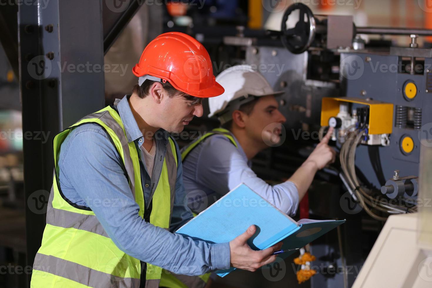 mannen industrieel ingenieur die een veiligheidshelm draagt terwijl hij in een zware industriële fabriek staat. het onderhoud van het werken aan industriële machines en het controleren van de installatie van het beveiligingssysteem in de fabriek. foto