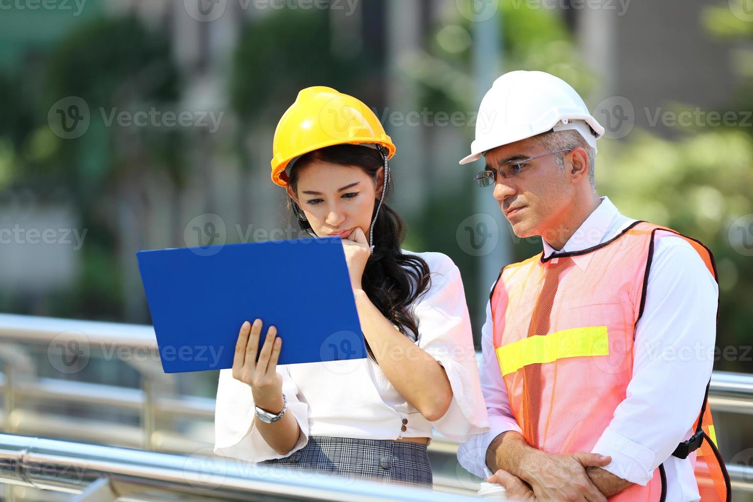 de ingenieur en zakenvrouw die op het klembord controleren bij de bouw van de bouwplaats. het concept van engineering, constructie, stadsleven en toekomst. foto