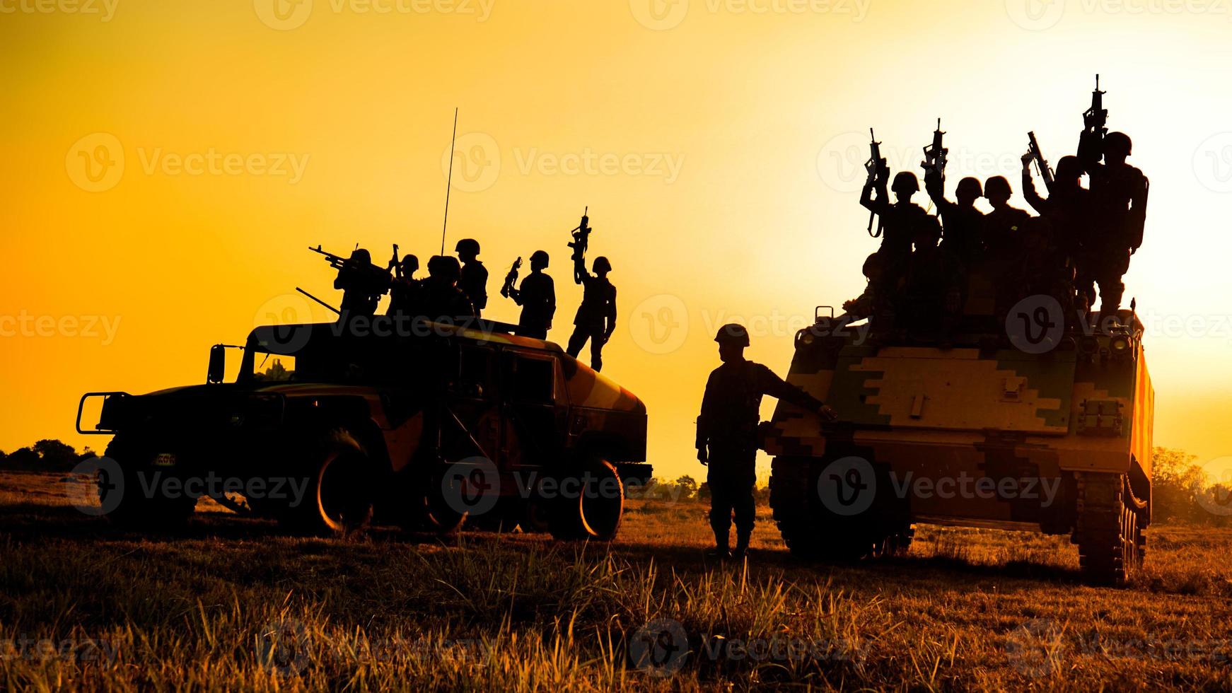 silhouetten van legersoldaten in de mist tegen een zonsondergang, mariniersteam in actie, omringd door vuur en rook, schietend met aanvalsgeweer en machinegeweer, aanvallende vijand foto